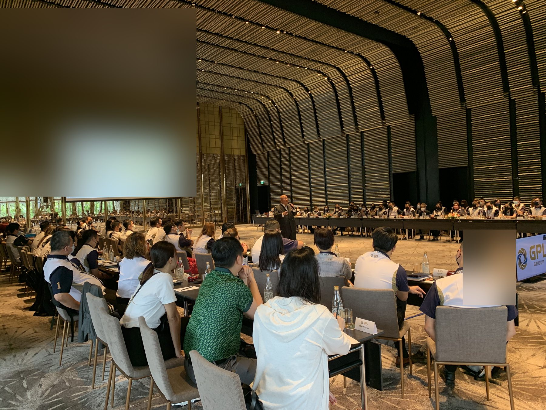 Room depth — full commercial team around the U-shaped table, Marcus presenting